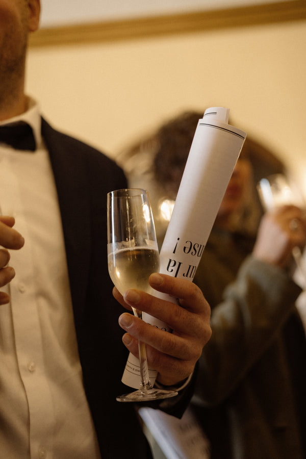Person holding a bottle of champagne and a glass with a blurred background